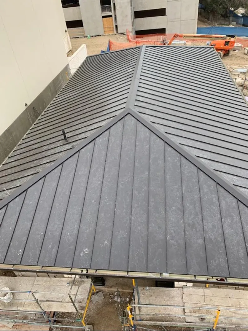 Commercial metal roof construction with crane equipment in Kyle